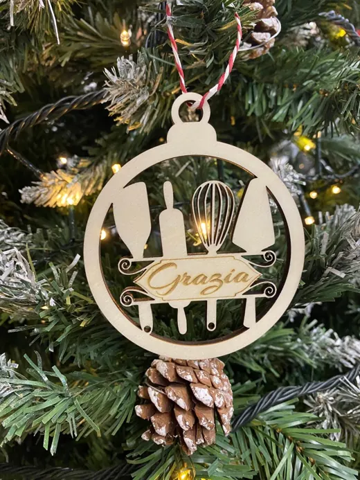 Pallina di Natale in legno con gli attrezzi da cucina traforati e il nome Grazia, appesa all'albero