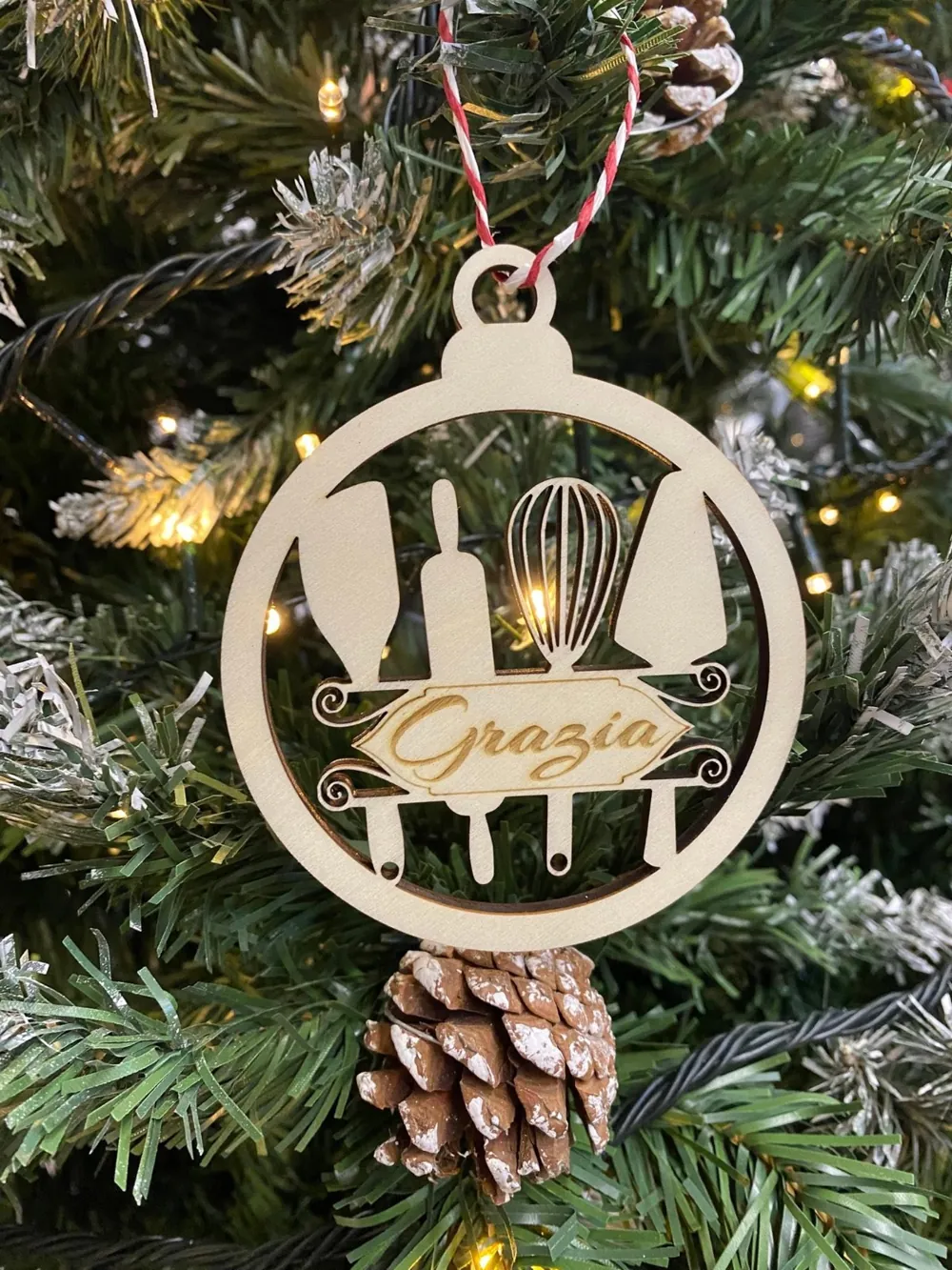 Pallina di Natale in legno con gli attrezzi da cucina traforati e il nome Grazia, appesa all'albero