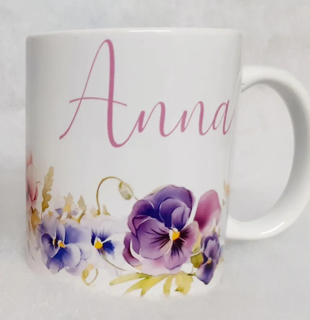 Tazza bianca col nome Anna in corsivo rosa e un bordo di viole del pensiero